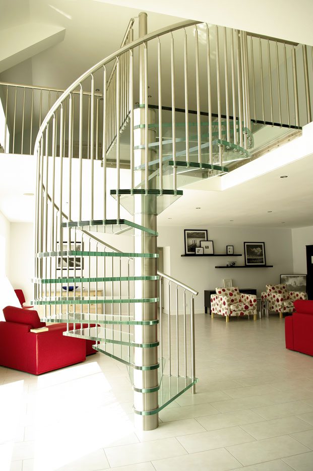 Glass Spiral Staircase in living room with red chairs and sofas
