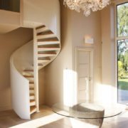 glass table in hallway with white walled spiral stair