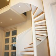 white enclosed wall spiral staircase with oak treads in hallway
