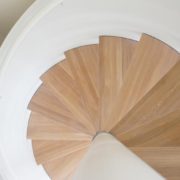 solid balustrade around a white steel spiral stair with oak steps