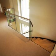 landing area in house with beige carpet and frameless glass