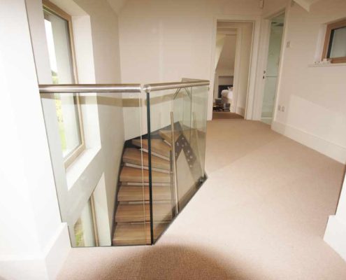 Bespoke-Staircase-Alresford-9 landing with light carpet and glass balustrade