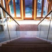 oak steps on a steel and glass staircase in a large hallway