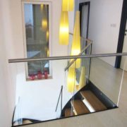 glass balustrade around a stairwell with bright yellow lights dangling