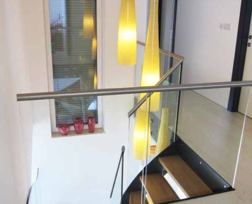 Modern-Stair-Berwick-Upon-Tweed-3 glass balustrade around a stairwell with bright yellow lights dangling
