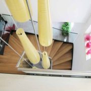 yellow light suspended down a stairwell containing a modern wood and steel staircase