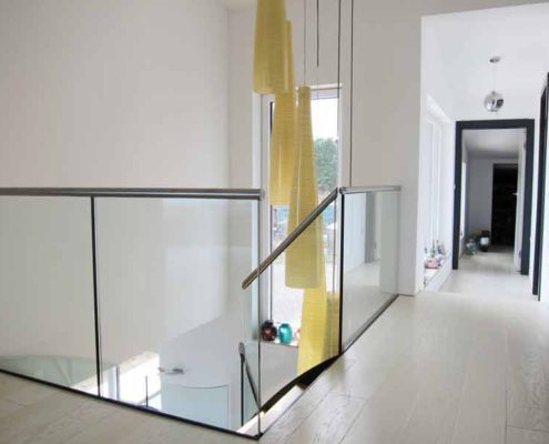 Modern-Stair-Berwick-Upon-Tweed-5 landing with large yellow suspended light down a stairwell with frameless glass around
