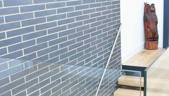 Modern-Staircase-Stamford-6 feature brick wall behind a straight oak staircase with stainless wall handrail