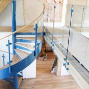 walkway with frameless glass panels and a blue spiral stair