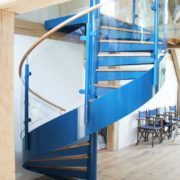 blue steel spiral staircase with curved glass panels and oak handrail