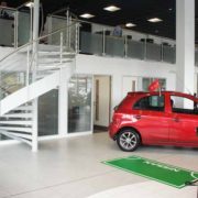 large white steel and stainless steel spiral staircase in a car showroom