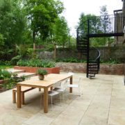 patio area to rear of house with wooden table and black spiral staircase
