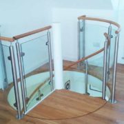 oak platform of a spiral staircase with landing balustrade with glass panels