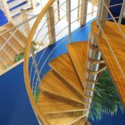 oak spiral staircase with horizontal rails with blue floor below