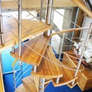 spiral stair in an office with stainless steel horizontal rails and oak handrail