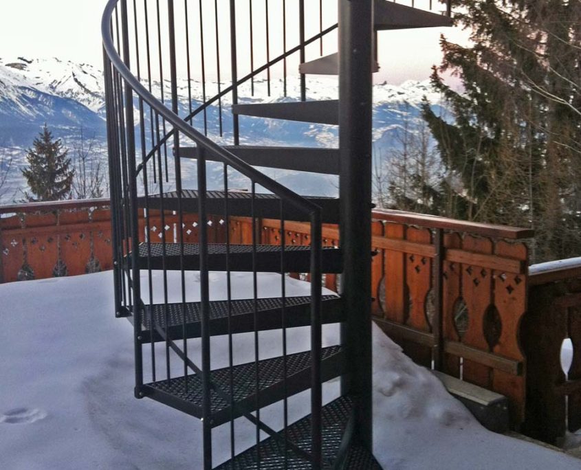 external spiral staircase in black with snowy mountains behind