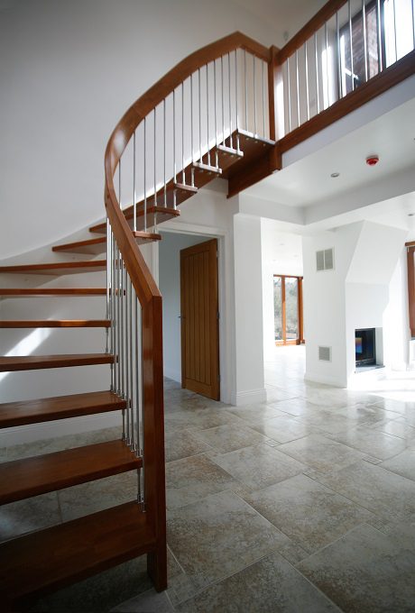 hallway with a staircase and curved handrail and open risers