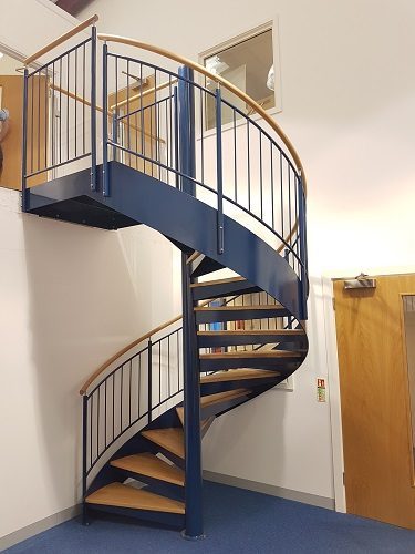 A blue spiral staircase in a office with a blue floor