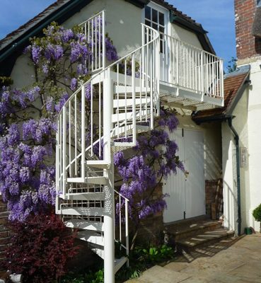 white external spiral staircase with purple flowers behind