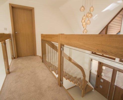 carpeted walkway in house with glass balustrade either side