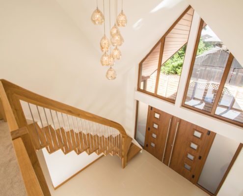 large hallway with suspended lights and floating timber staircase