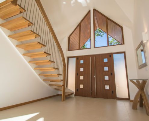 hallway of house with large front door and floating staircase