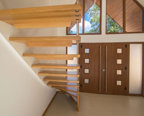 View behind open riser staircase with front door beyond