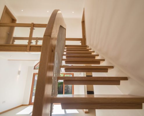 Looking up a floating wood stair in a hallway