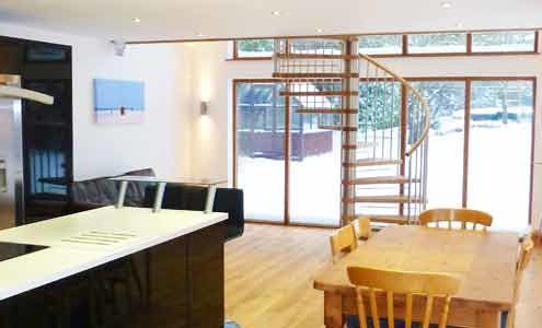 kitchen dining area with large spiral stair and large window to rear