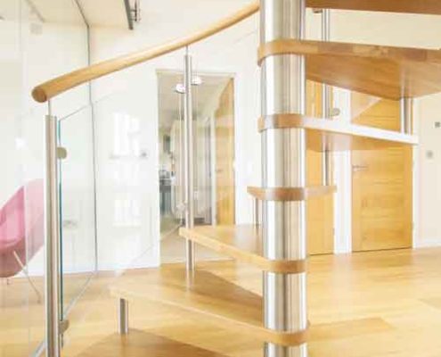bottom section of an open riser oak spiral stair with stainless column