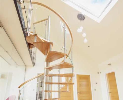 spiral stair leading up to a walkway beneath a roof window