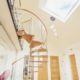 spiral stair leading up to a walkway beneath a roof window