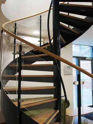 Curved-Acrylic-Panels on the side of a black steel and wooden spiral stair