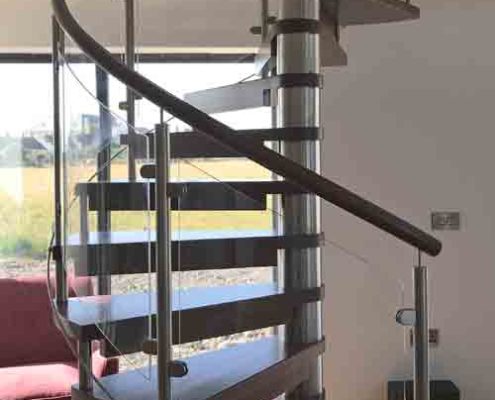 dark wood spiral stair Infront of window showing countryside