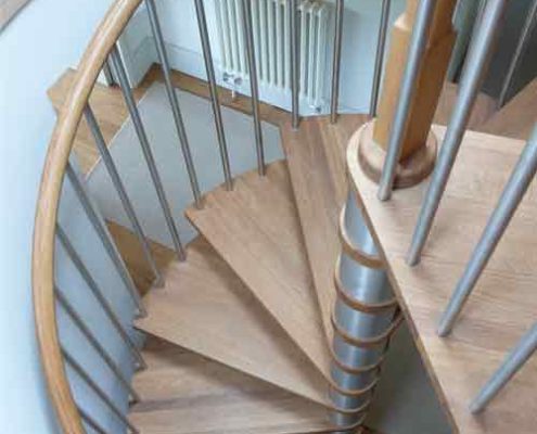 oak tread spiral staircase set within a circular opening with stainless spindles