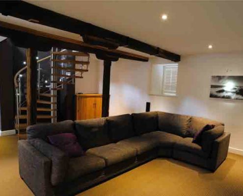 large living room with big black sofa Infront of spiral staircase