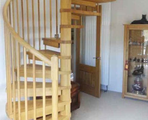 solid oak spiral staircase with timber spindles in a living room