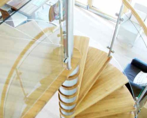 looking down on an oak spiral staircase with curved glass panels