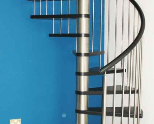 black timber spiral stair with stainless steel balustrade with blue wall behind
