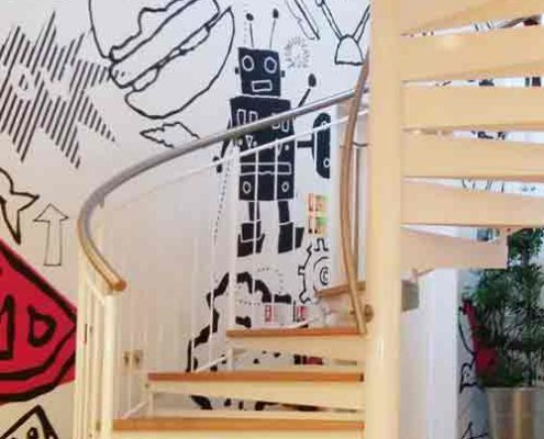white steel spiral stair with oak steps in front of a funky wall