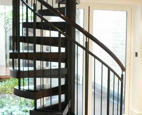 black spiral staircase with dark wood handrail and steps