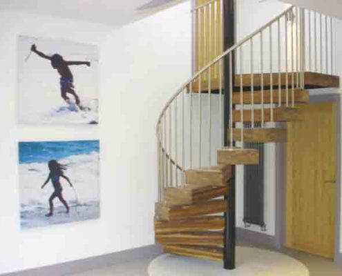 spiral stair with chunky walnut steps and stainless balustrade