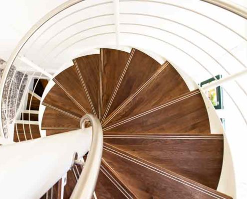 looking down on a timber treads spiral staircase with white wall behind