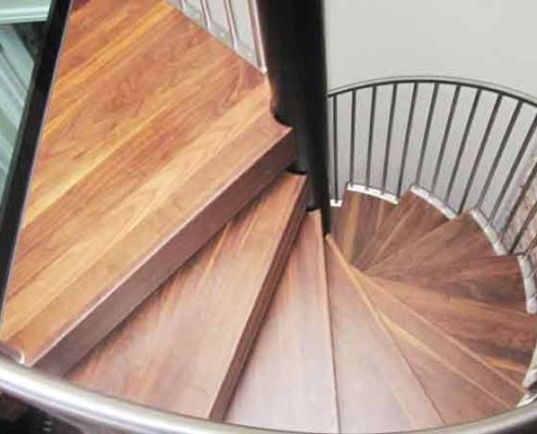 looking down on a walnut step spiral staircase alongside a glass floor