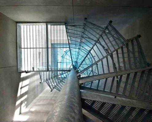 looking up through the perforated steel steps of a galvanised spiral staircase