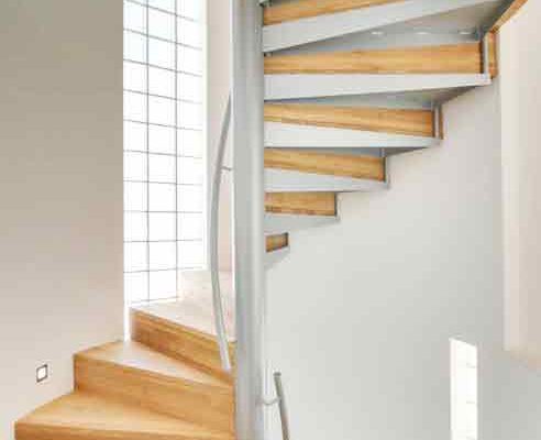 grey and timber spiral staircase with curved white wall behind