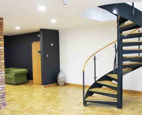 black and wood spiral stair on a timber floor in a commercial setting