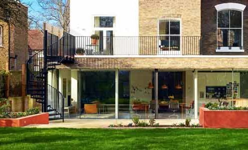 back of house with large balcony and black spiral staircase