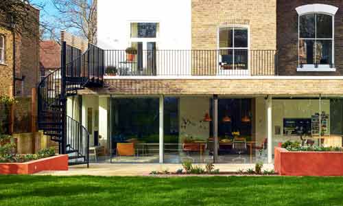 back of house with large balcony and black spiral staircase