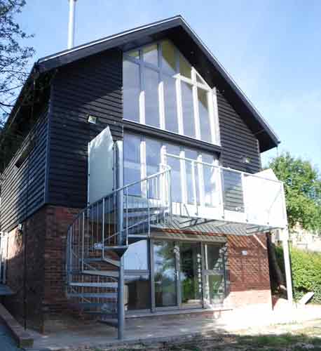 large steel balcony to side a black house with a spiral staircase